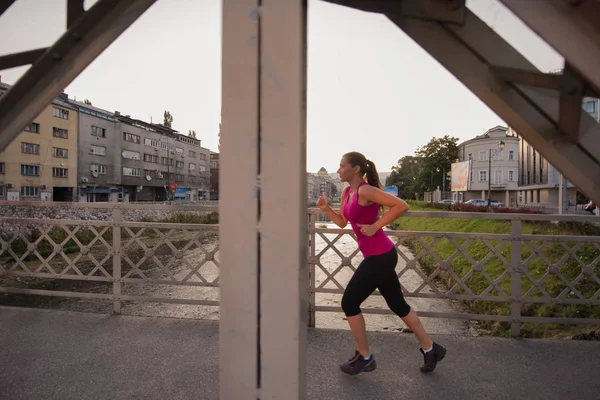 Femme jogging à travers le pont au matin ensoleillé — Photo