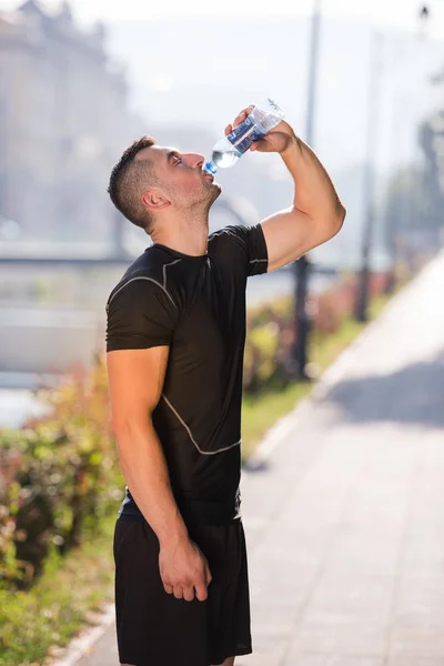 Ο άνθρωπος πόσιμο νερό από ένα μπουκάλι μετά το τρέξιμο — Φωτογραφία Αρχείου