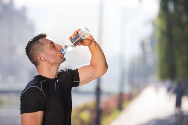 Homem água potável de uma garrafa depois de correr — Fotografia de Stock