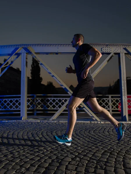 Muž běhat přes most ve městě — Stock fotografie