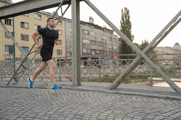 Homme jogging à travers le pont au matin ensoleillé — Photo