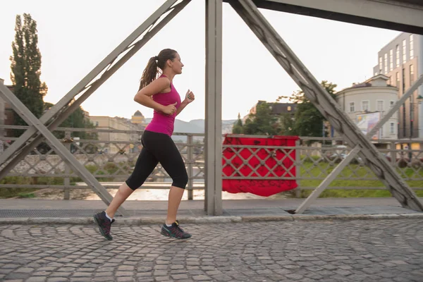 Kobieta, jogging przez most w słoneczny poranek — Zdjęcie stockowe