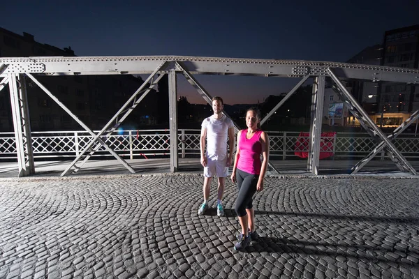 Couple jogging across the bridge in the city — Stock Photo, Image