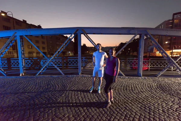 Couple jogging à travers le pont dans la ville — Photo