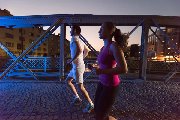 Couple jogging à travers le pont dans la ville — Photo