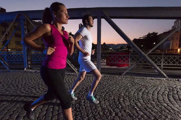 Couple jogging à travers le pont dans la ville — Photo