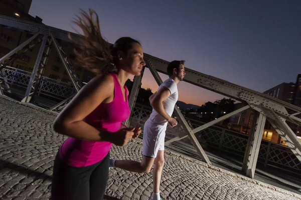 Para joggingu przez most w mieście — Zdjęcie stockowe