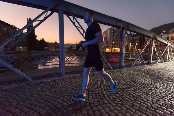 Muž běhat přes most ve městě — Stock fotografie