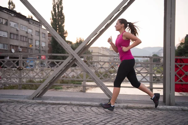 Mulher correndo através da ponte na manhã ensolarada — Fotografia de Stock