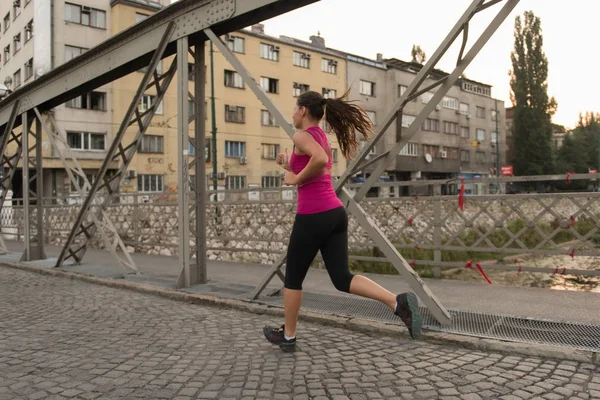 Donna che corre attraverso il ponte al mattino di sole — Foto Stock