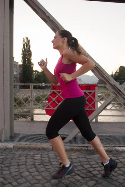 Femme jogging à travers le pont au matin ensoleillé — Photo