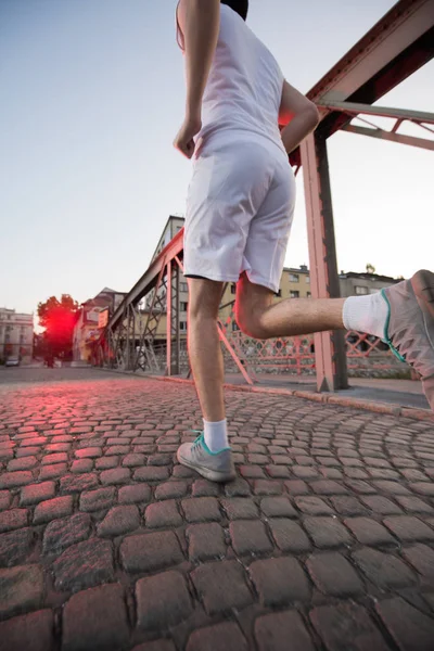 Człowiek, jogging przez most w słoneczny poranek — Zdjęcie stockowe