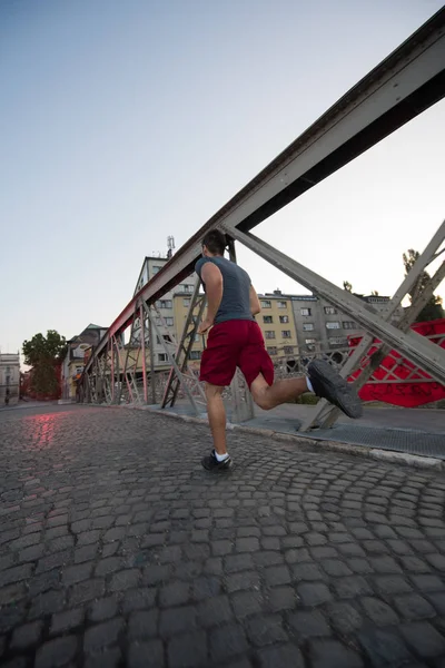 Homme jogging à travers le pont au matin ensoleillé — Photo