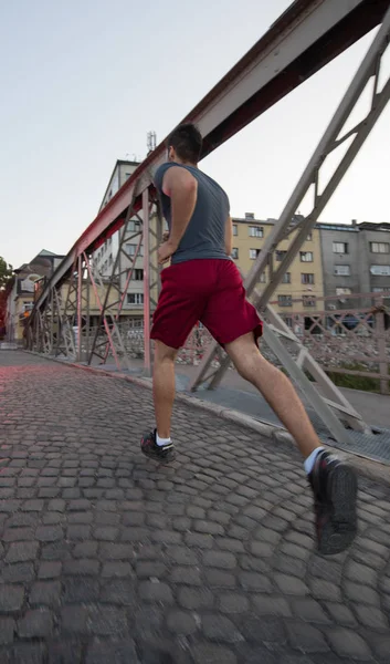 Hombre corriendo a través del puente en la mañana soleada —  Fotos de Stock