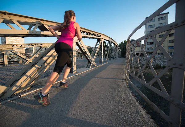 Mulher correndo através da ponte na manhã ensolarada — Fotografia de Stock