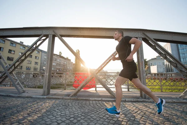 Homem correndo através da ponte na manhã ensolarada — Fotografia de Stock