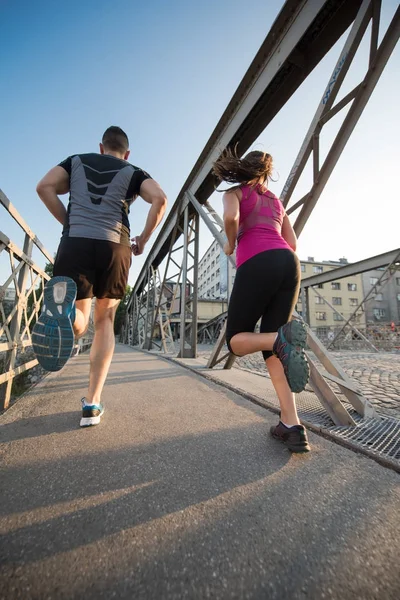 Pareja joven corriendo a través del puente en la ciudad —  Fotos de Stock