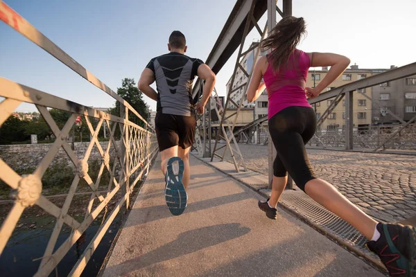 Fiatal pár, jogging, át a hídon a városban — Stock Fotó