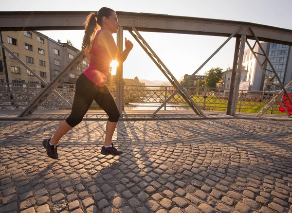 Donna che corre attraverso il ponte al mattino di sole — Foto Stock