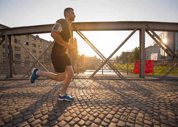 Uomo che corre attraverso il ponte al mattino di sole — Foto Stock