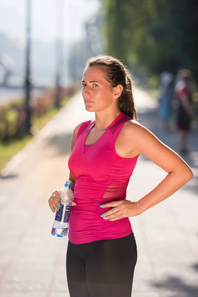 Женщина пьет воду из бутылки после пробежки — стоковое фото