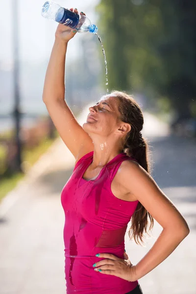 Женщина льет воду из бутылки на голову — стоковое фото