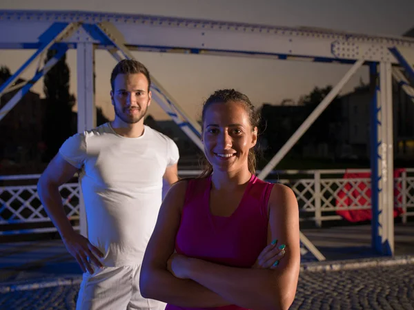 Portret van paar joggen over de brug in de stad — Stockfoto