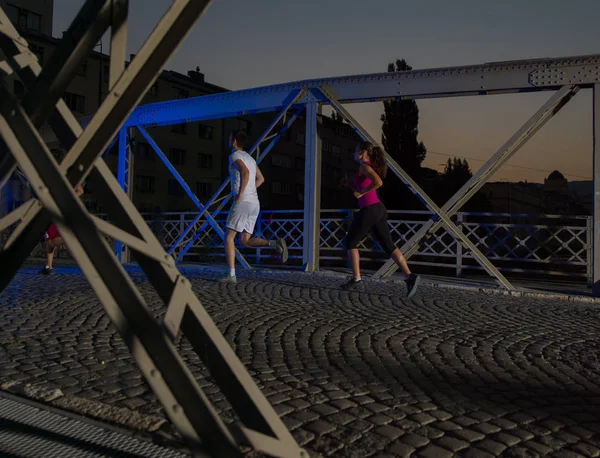 Портрет пары бегущей через мост в городе — стоковое фото