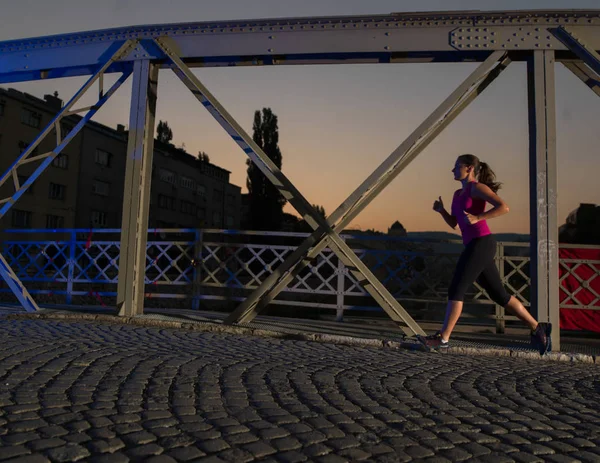 Žena, běhat přes most ve městě — Stock fotografie