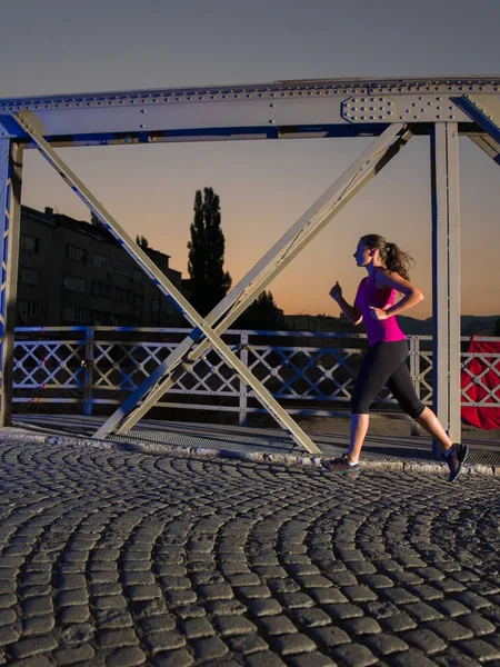 Kvinna som jogging över bron i staden — Stockfoto