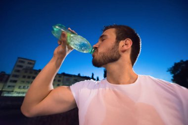 oturum şehirde çalışan bir geceden sonra içme suyu atletik genç adam