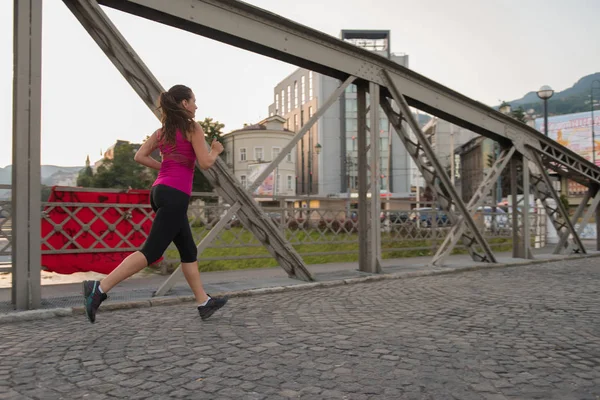 都市の晴れた朝で橋を渡ってジョギング若いスポーティな女性 — ストック写真
