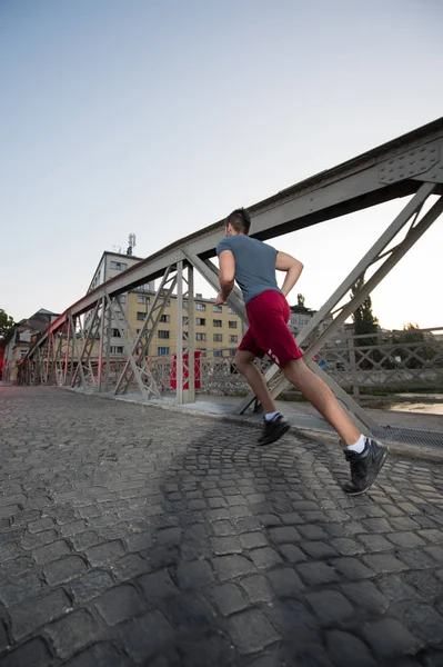 Giovane Sportivo Che Corre Attraverso Ponte Mattino Sole Città — Foto Stock