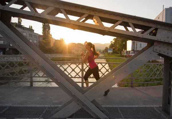 都市の晴れた朝で橋を渡ってジョギング若いスポーティな女性 — ストック写真