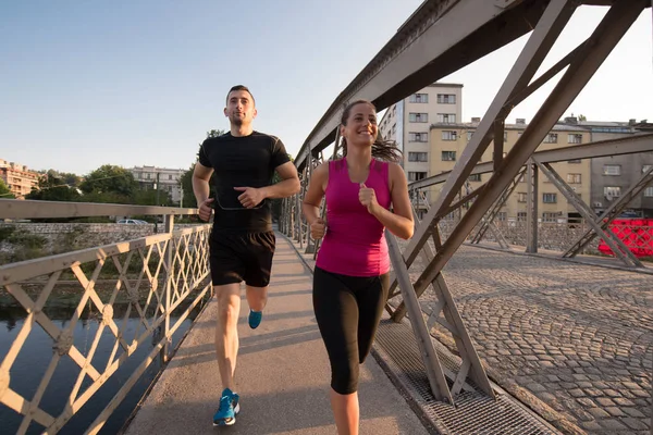 都市スポーツ 晴れた朝に市内の橋を渡ってジョギング健康な若いカップル — ストック写真