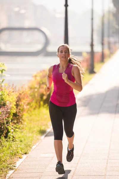 都市の晴れた朝にジョギング若いスポーティな女性 — ストック写真