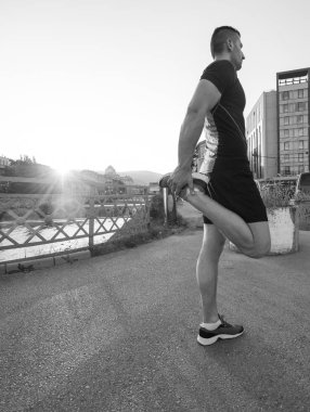 Isınma ve germe şehrin güneşli sabah sokak üzerinde çalıştırmak için hazırlarken sporcu adam