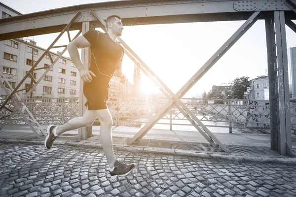Młody Człowiek Sportowy Jogging Przez Most Słoneczny Poranek Mieście — Zdjęcie stockowe