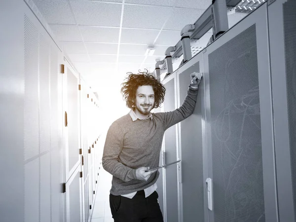 在现代数据中心服务器室的平板电脑上工作的男性It工程师 — 图库照片