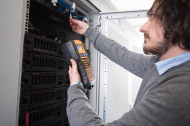 Genç bu büyük veri merkezindeki sunucu üzerinde dijital kablo çözümleyicisini kullanarak teknisyen