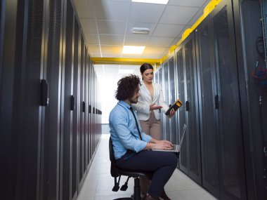 Bilgisayar kullanarak veri merkezindeki sunucularda birlikte çalışan genç teknisyenler.