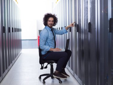 sunucu odasında bir dizüstü bilgisayar üzerinde çalışan mühendis