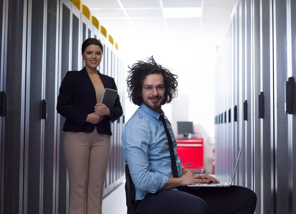 Equipe de jovens técnicos trabalhando juntos em servidores — Fotografia de Stock