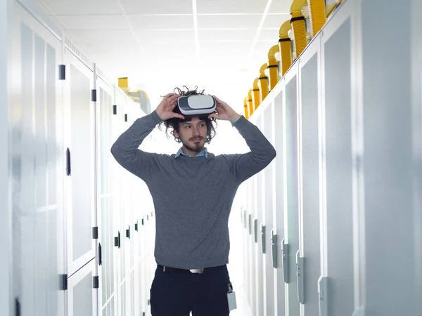 young IT engineer using virtual reality headset over server room background