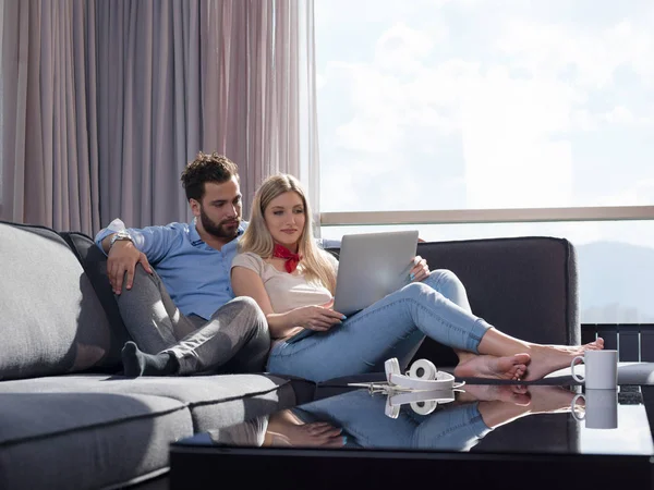 若いカップルの贅沢なソファー ソファのリビング ルームでラップトップ コンピューターの読み取りを使用して家でリラックス — ストック写真