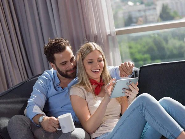 Genç Çift Oturma Odasında Kanepede Oturup Tablet Bilgisayar Okuyarak Rahatlıyor — Stok fotoğraf