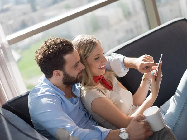 Pareja Joven Relajándose Casa Usando Tabletas Leyendo Sala Estar Sofá —  Fotos de Stock