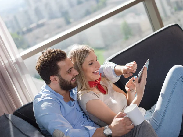 Pareja Joven Relajándose Casa Usando Tabletas Leyendo Sala Estar Sofá —  Fotos de Stock