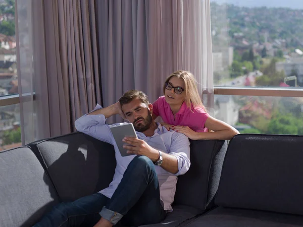 Pareja Joven Relajándose Casa Usando Tabletas Leyendo Sala Estar Sofá —  Fotos de Stock