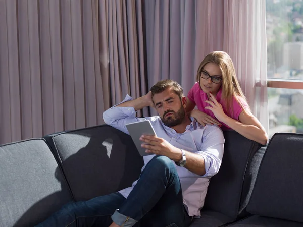 Pareja Joven Relajándose Casa Usando Tabletas Leyendo Sala Estar Sofá —  Fotos de Stock